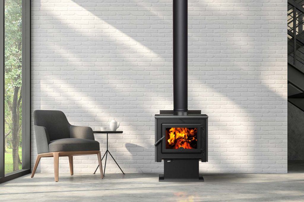 a lit wood-burning stove against a white brick wall with a modern chair and table next to it