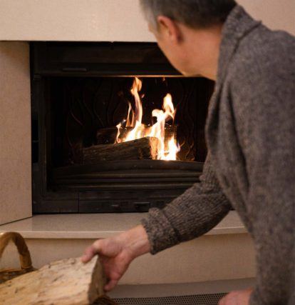 a man putting wood into a burning fireplace